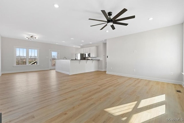 unfurnished living room with light wood-type flooring and ceiling fan