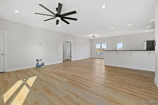 unfurnished living room featuring ceiling fan and light hardwood / wood-style flooring