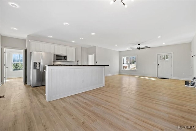 kitchen with appliances with stainless steel finishes, light hardwood / wood-style flooring, white cabinets, and plenty of natural light