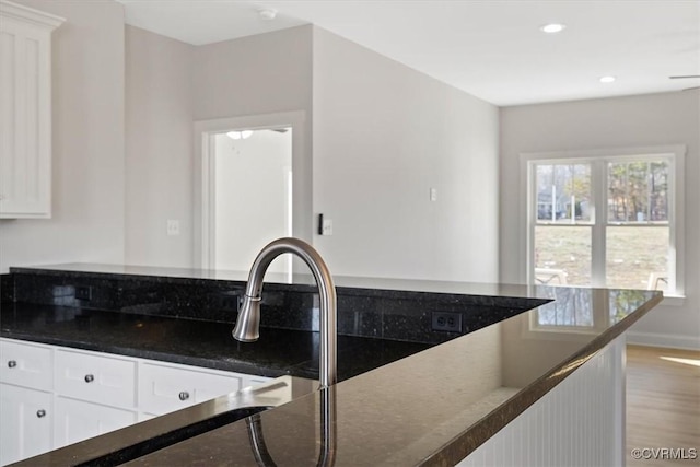 kitchen with dark stone countertops, light hardwood / wood-style flooring, and white cabinetry