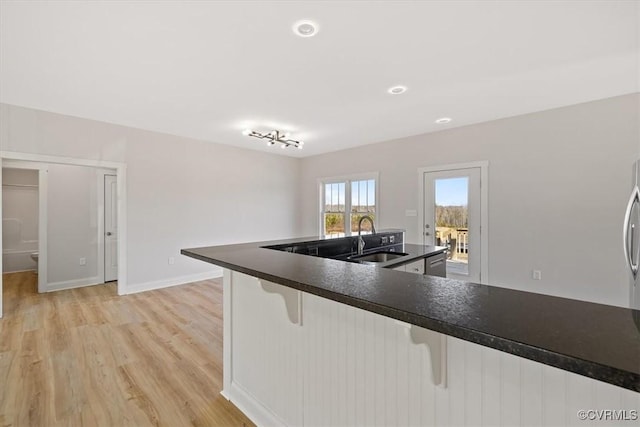 kitchen featuring sink, light hardwood / wood-style flooring, dishwasher, and a kitchen bar