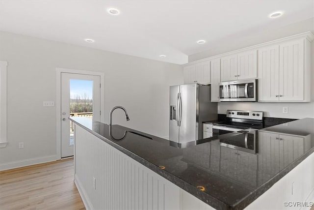 kitchen featuring white cabinets, light hardwood / wood-style flooring, kitchen peninsula, and appliances with stainless steel finishes