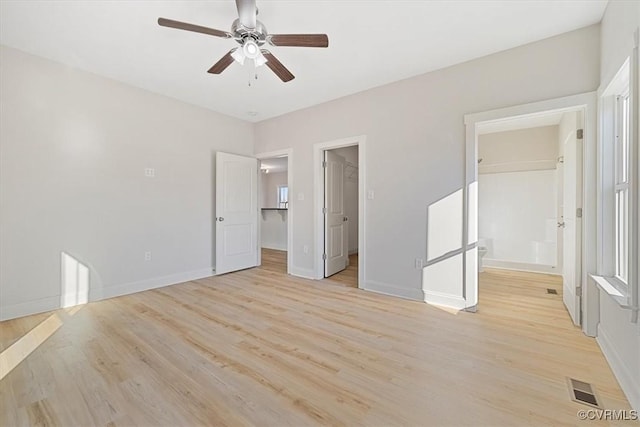 unfurnished bedroom with a closet, light hardwood / wood-style floors, ceiling fan, a walk in closet, and ensuite bathroom