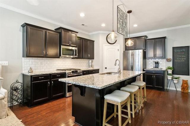 kitchen featuring a kitchen island with sink, a breakfast bar area, appliances with stainless steel finishes, sink, and backsplash