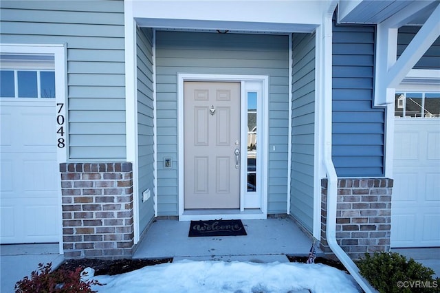 snow covered property entrance featuring a garage