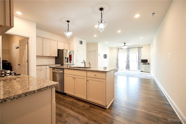 kitchen featuring sink, decorative light fixtures, light stone counters, an island with sink, and appliances with stainless steel finishes