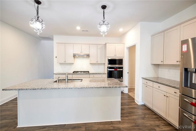 kitchen with stainless steel appliances, sink, an island with sink, hanging light fixtures, and light stone countertops