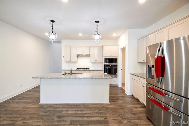 kitchen featuring decorative light fixtures, stainless steel appliances, a center island with sink, and sink