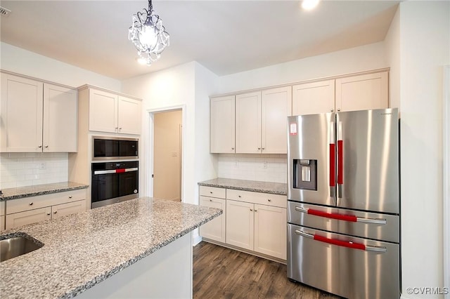 kitchen featuring light stone countertops, decorative backsplash, hanging light fixtures, and appliances with stainless steel finishes