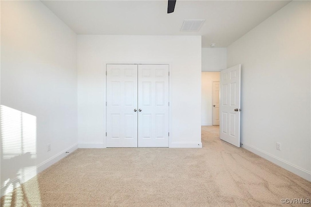 unfurnished bedroom with ceiling fan, light colored carpet, and a closet