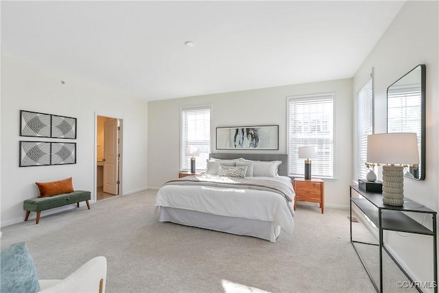 bedroom with multiple windows, light carpet, and connected bathroom