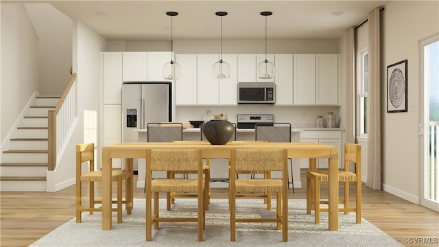 kitchen with appliances with stainless steel finishes, light wood-type flooring, white cabinets, and decorative light fixtures