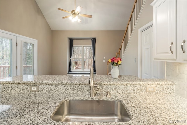 kitchen with sink, ceiling fan, white cabinetry, tasteful backsplash, and light stone countertops