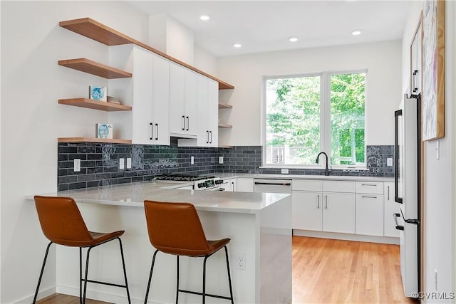 kitchen with stainless steel appliances, a breakfast bar area, white cabinets, and kitchen peninsula