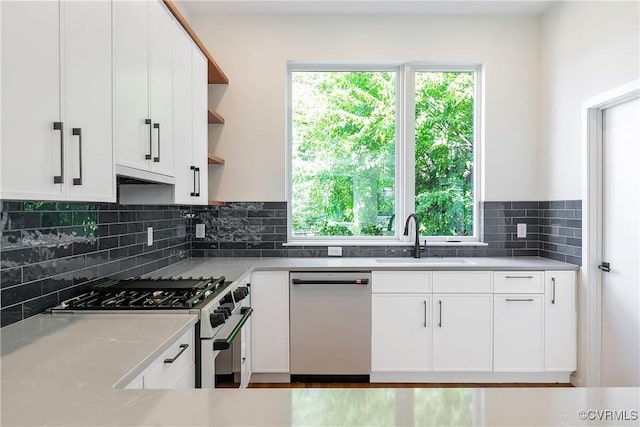 kitchen with stainless steel appliances, white cabinets, decorative backsplash, and sink