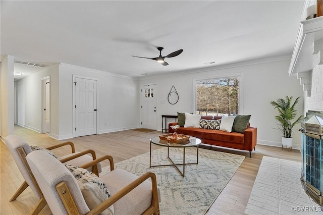 living room featuring ornamental molding, light wood-type flooring, ceiling fan, and a brick fireplace