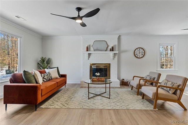 living room featuring a fireplace, ornamental molding, and a healthy amount of sunlight