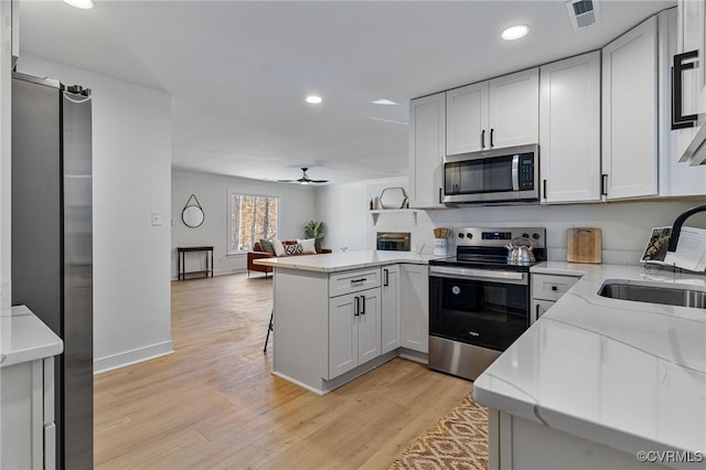 kitchen with kitchen peninsula, stainless steel appliances, sink, and white cabinetry