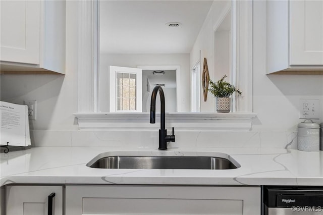 interior details with sink, light stone countertops, dishwasher, and white cabinetry