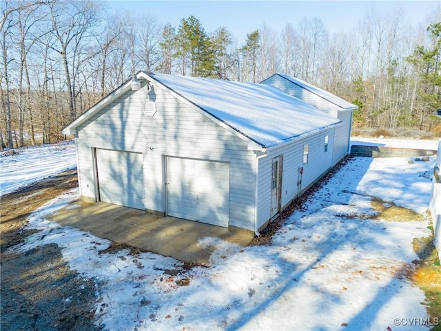 view of snowy exterior featuring a garage