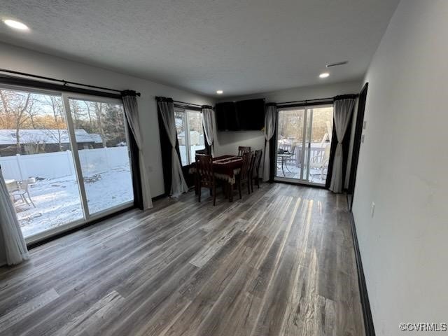 unfurnished dining area featuring dark wood-type flooring and a textured ceiling