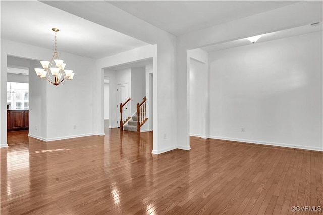 unfurnished room featuring an inviting chandelier and hardwood / wood-style flooring