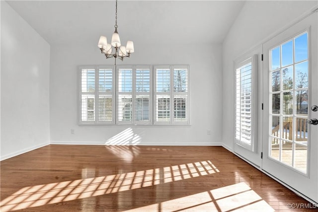 unfurnished dining area with an inviting chandelier, hardwood / wood-style floors, and vaulted ceiling