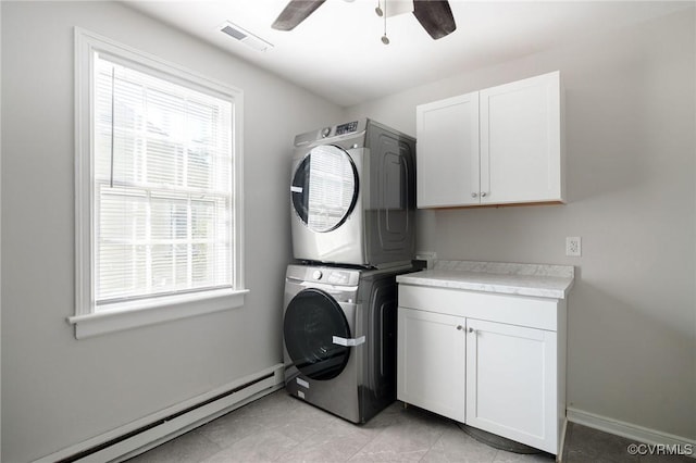 laundry area with cabinets, stacked washer and dryer, plenty of natural light, and a baseboard radiator