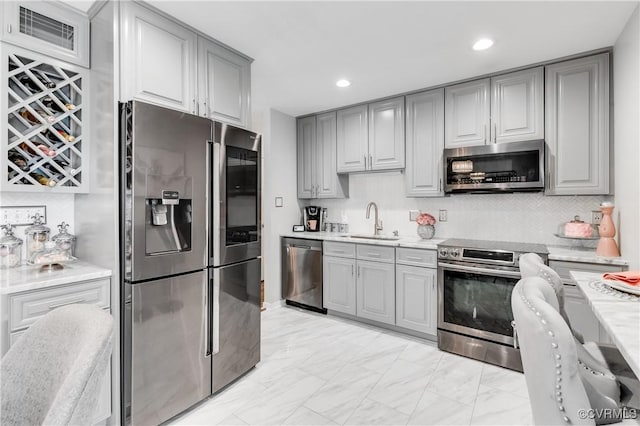 kitchen with decorative backsplash, appliances with stainless steel finishes, gray cabinetry, and sink