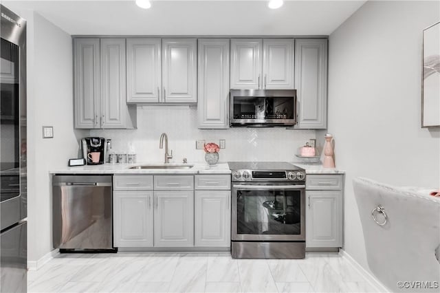 kitchen featuring stainless steel appliances, decorative backsplash, gray cabinetry, and sink