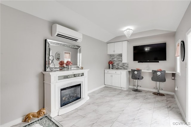 kitchen featuring a high end fireplace, white cabinets, vaulted ceiling, tasteful backsplash, and a wall unit AC