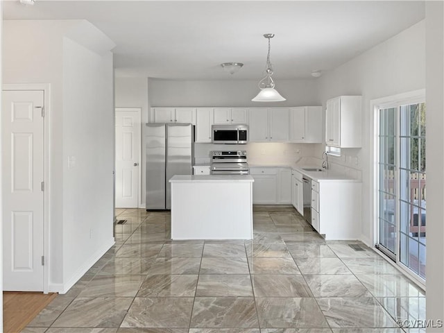 kitchen featuring hanging light fixtures, a kitchen island, white cabinetry, appliances with stainless steel finishes, and sink