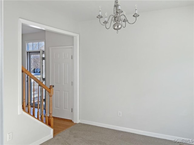 spare room with carpet and a chandelier