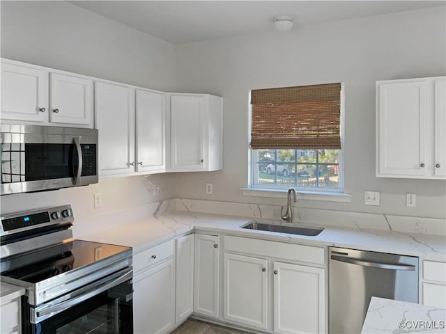 kitchen featuring sink, stainless steel appliances, light stone counters, and white cabinetry