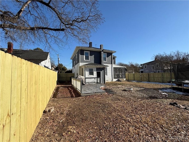 rear view of house with a wooden deck, a sunroom, and a trampoline