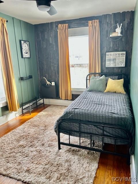 bedroom with multiple windows, ceiling fan, and hardwood / wood-style flooring