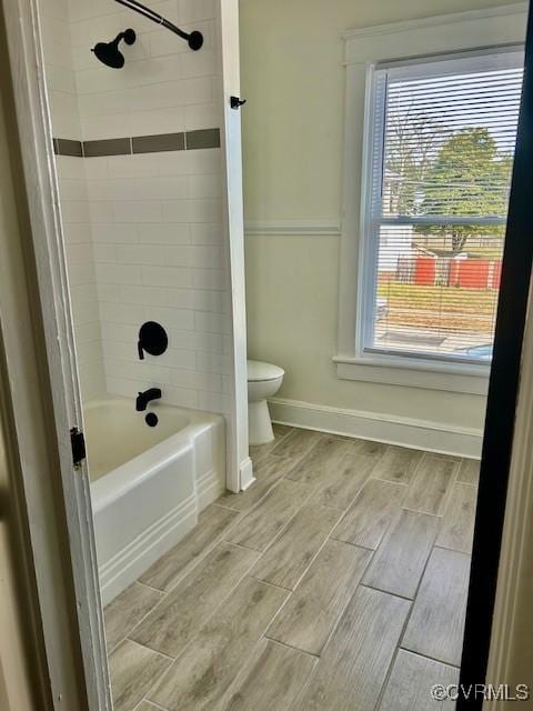 bathroom with toilet and tiled shower / bath combo