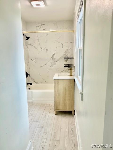 bathroom with tiled shower / bath, wood-type flooring, and vanity