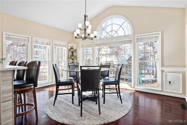 dining space with dark wood-type flooring, vaulted ceiling, a wealth of natural light, and a chandelier