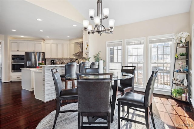 dining room with lofted ceiling, dark hardwood / wood-style flooring, and a notable chandelier