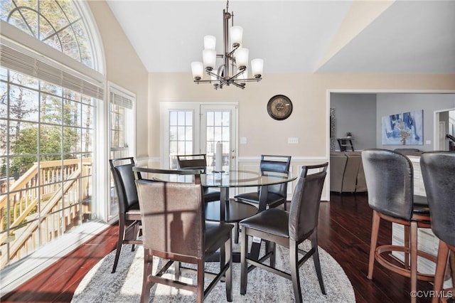 dining area featuring lofted ceiling, a healthy amount of sunlight, dark wood-type flooring, and a chandelier