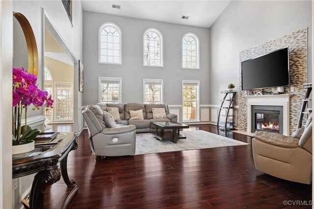 living room featuring a towering ceiling, a wealth of natural light, and dark wood-type flooring