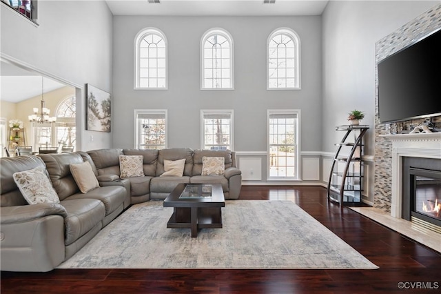 living room with a healthy amount of sunlight, a towering ceiling, a chandelier, and wood-type flooring