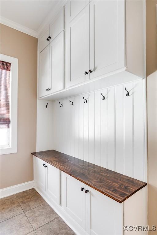 mudroom with light tile patterned floors and ornamental molding