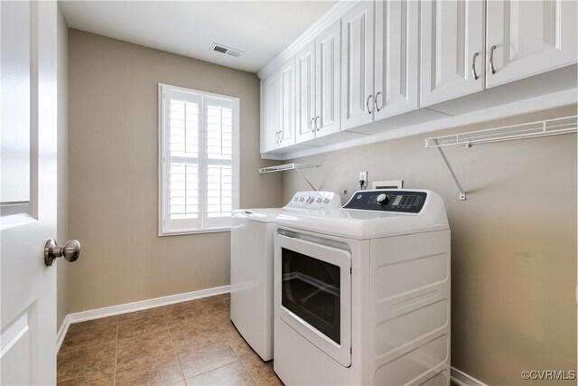 laundry room featuring cabinets, light tile patterned floors, and washing machine and clothes dryer