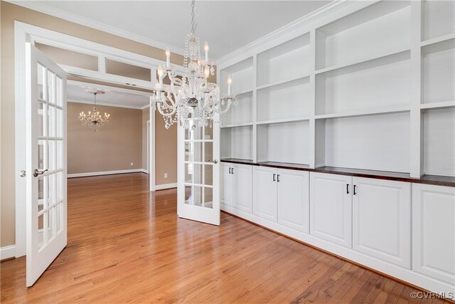 unfurnished dining area featuring light hardwood / wood-style flooring, french doors, a chandelier, and ornamental molding