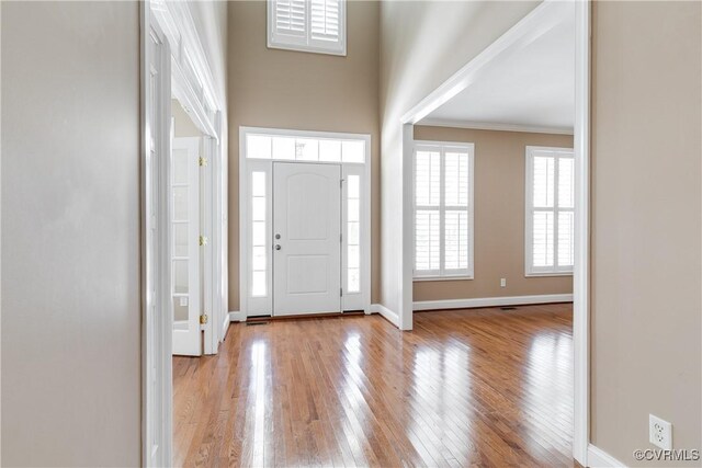 foyer entrance with ornamental molding and light wood-type flooring