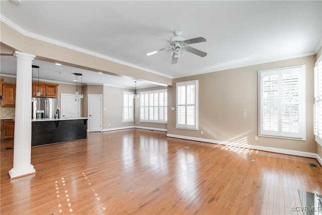 unfurnished living room featuring ceiling fan, light hardwood / wood-style floors, ornamental molding, and ornate columns