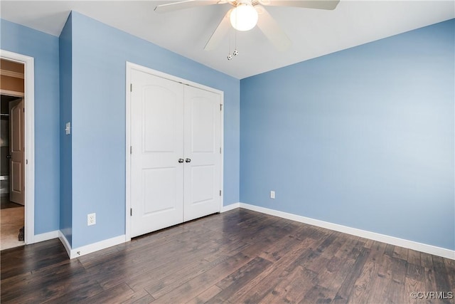 unfurnished bedroom with dark wood-style floors, a closet, a ceiling fan, and baseboards