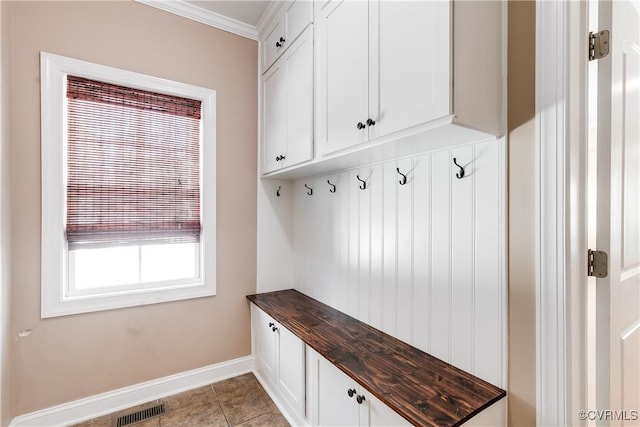 mudroom featuring visible vents, crown molding, baseboards, and light tile patterned floors